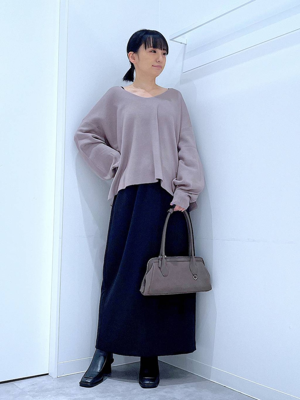 ブラック系のスカート、ブラウン系のニット/セーター、ブラック系のブーツを着用したレディースの秋コーディネートの2枚目の写真