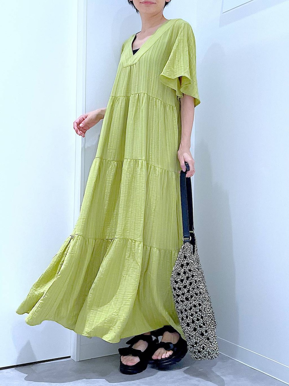 ブラック系のトートバッグ、ブラック系のサンダル、グリーン系のワンピースを着用したレディースの夏コーディネートの6枚目の写真