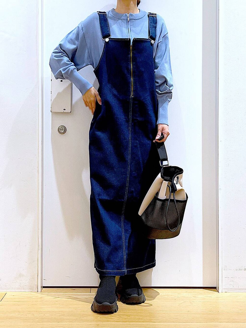 ブルー系のジャンパースカート、ブルー系のカーディガン/ボレロ、ブラック系のブーツを着用したレディースの春コーディネートの6枚目の写真