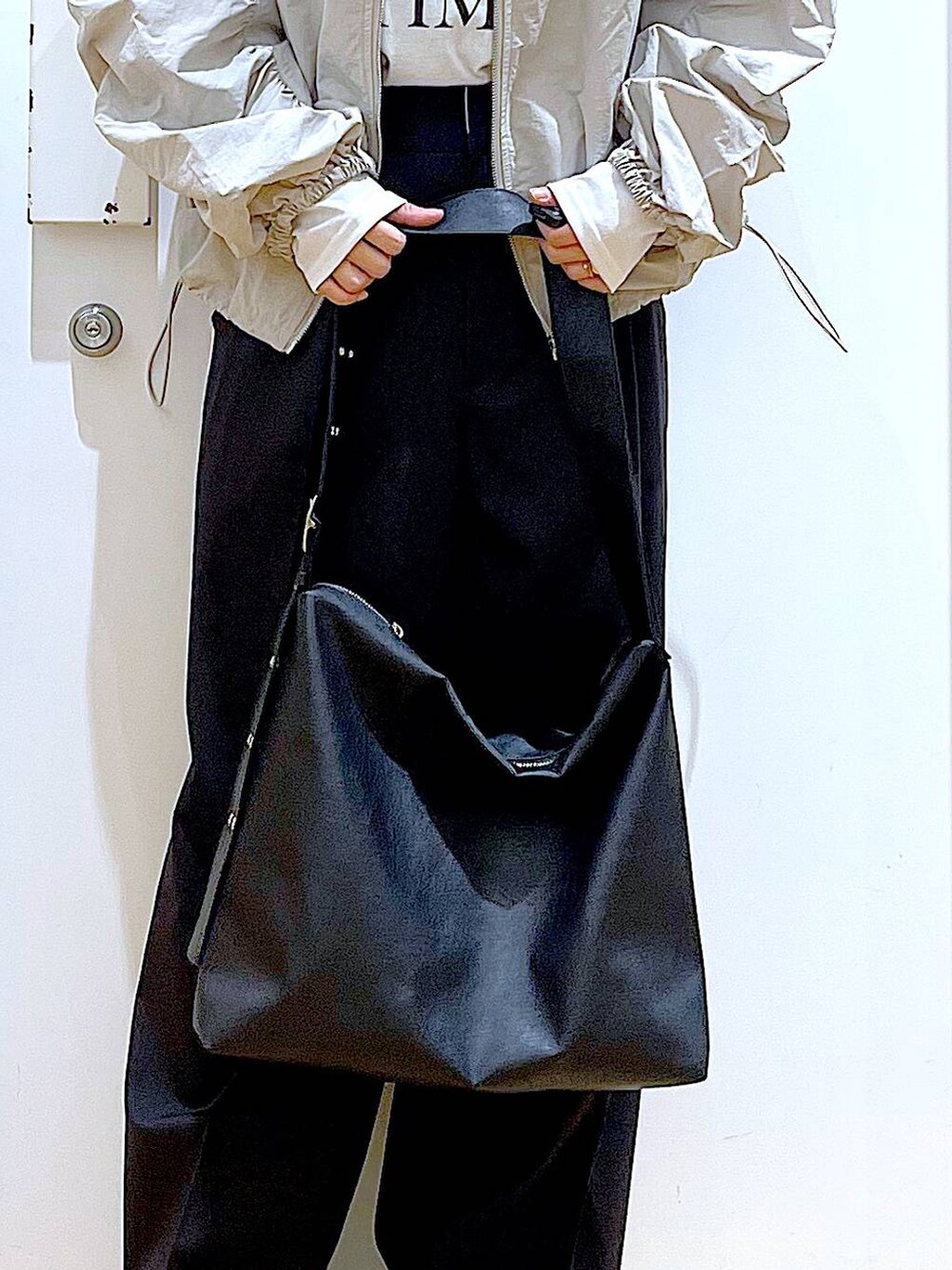 ブラック系のスラックス、ブラック系のスニーカー、ブラック系のショルダーバッグを着用したレディースの春コーディネートの9枚目の写真