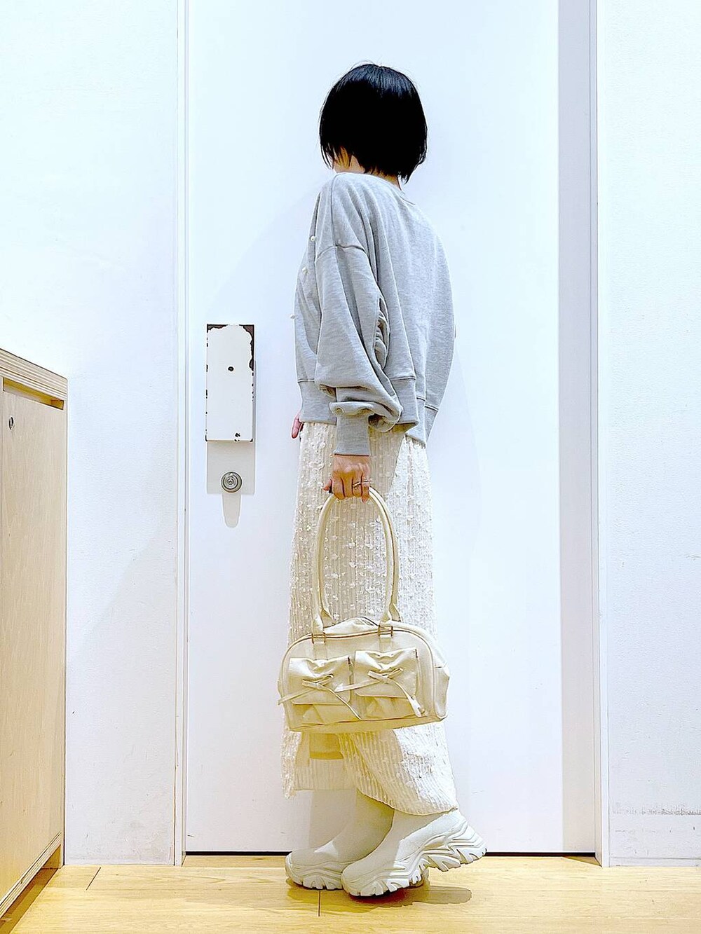 ホワイト系のハンドバッグ、グレー系のスウェット、ベージュ系のブーツを着用したレディースの秋コーディネートの3枚目の写真