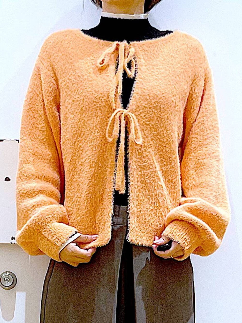 ブラック系のニット/セーター、ベージュ系のブーツ、ブラック系のショルダーバッグを着用したレディースの冬コーディネートの7枚目の写真