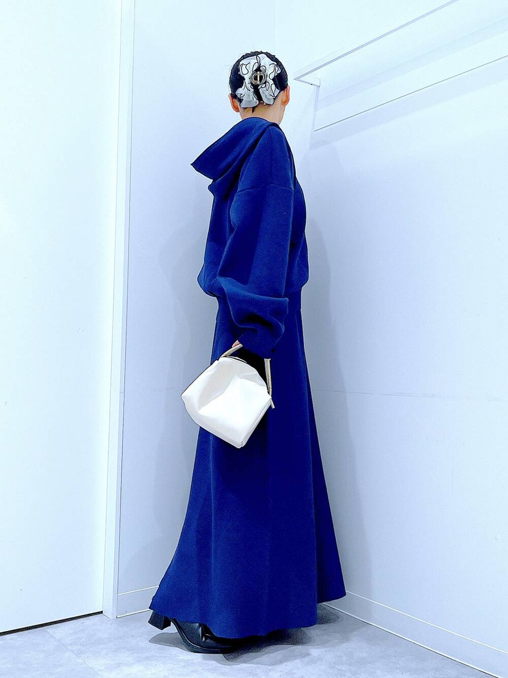 ブラック系のブーツ、ホワイト系のショルダーバッグ、ブルー系のスカートを着用したレディースの冬コーディネートの4枚目の写真