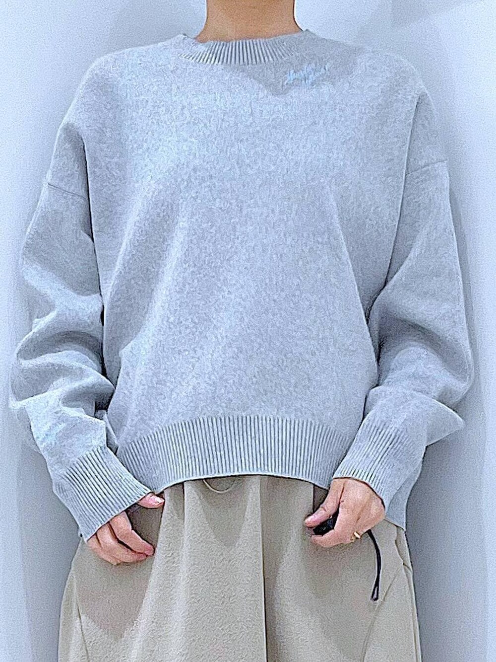 グレー系のニット/セーター、ブラウン系のショルダーバッグ、グレー系のスカートを着用したレディースの春コーディネートの7枚目の写真