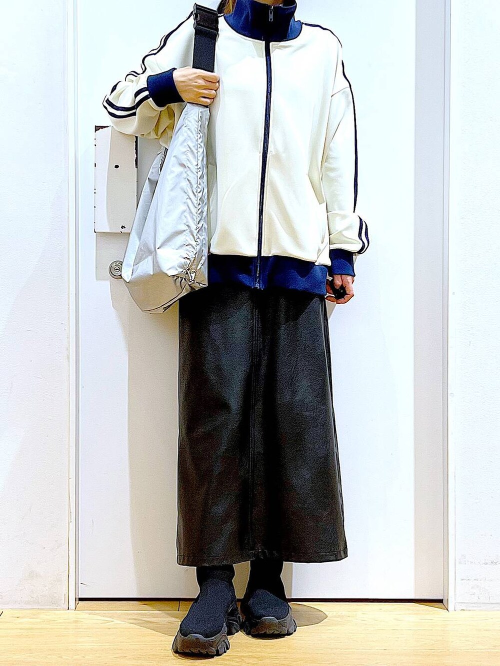 ブラック系のブーツ、ブラック系のスカート、シルバー系のショルダーバッグを着用したレディースの冬コーディネートの6枚目の写真