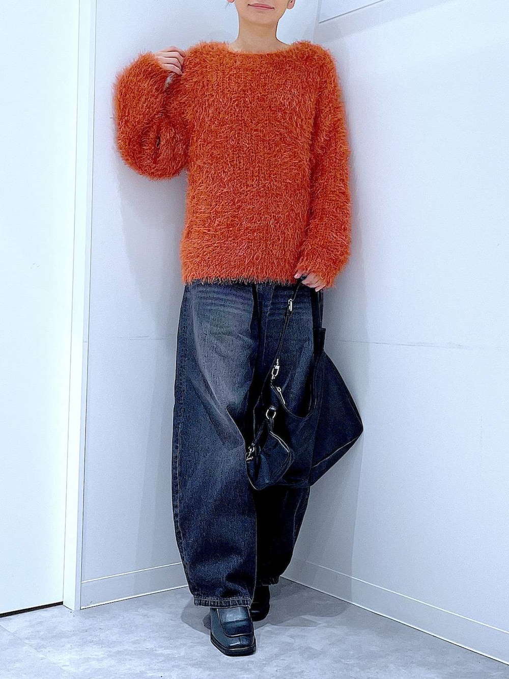 ブラック系のデニムパンツ、ブラック系のブーツ、ブラック系のショルダーバッグを着用したレディースの秋コーディネートの6枚目の写真