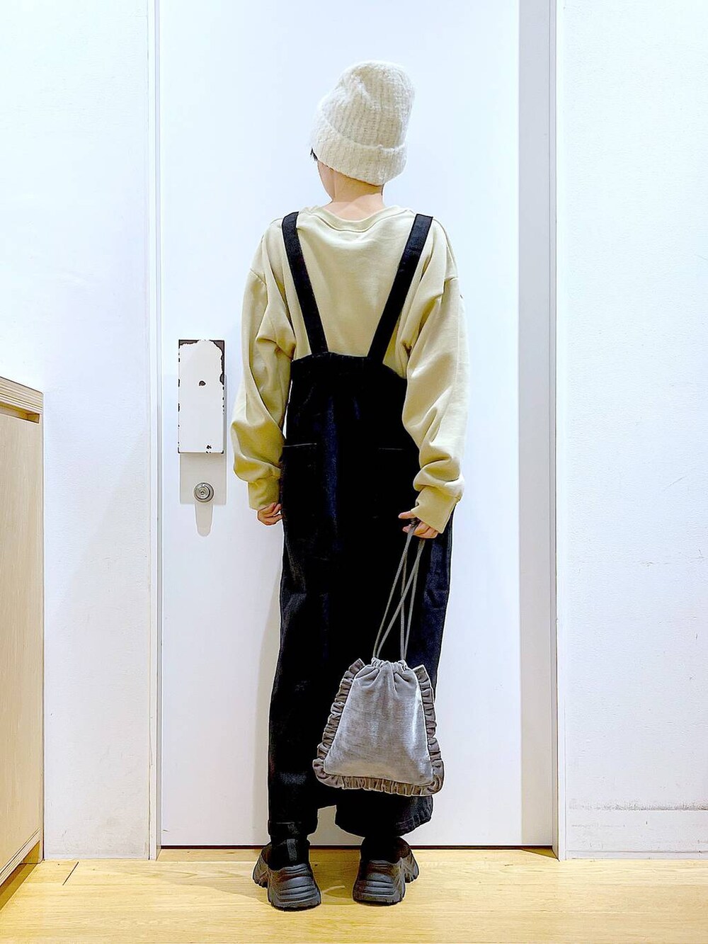 グレー系のジャンパースカート、グレー系のショルダーバッグ、ブラック系のブーツを着用したレディースの冬コーディネートの5枚目の写真