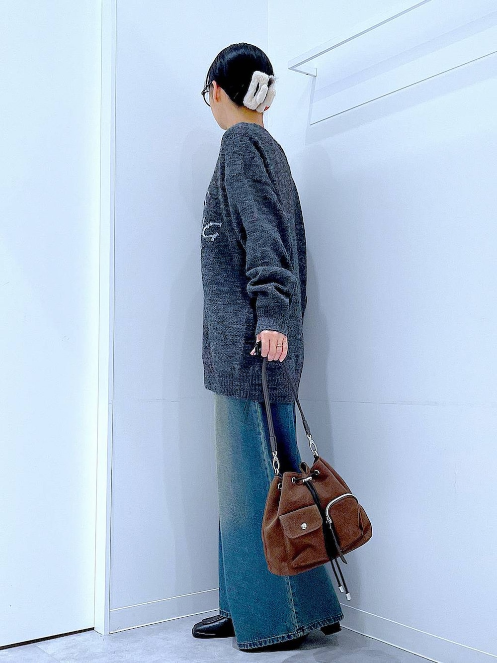 ブラウン系のショルダーバッグ、ブルー系のデニムパンツ、ブラック系のブーツを着用したレディースの冬コーディネートの3枚目の写真