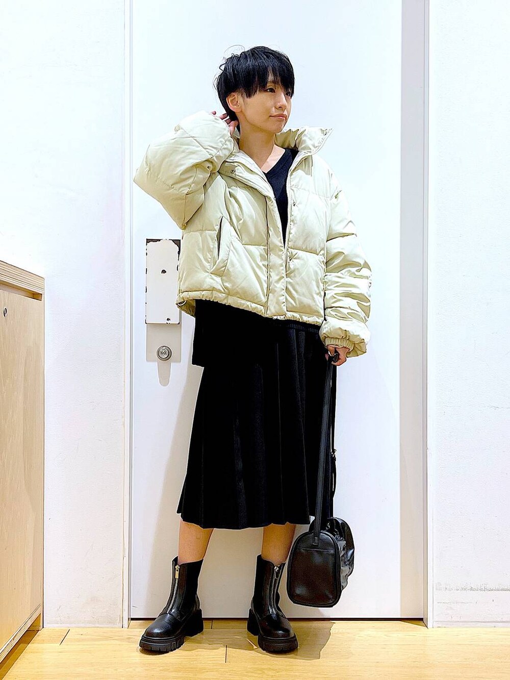 イエロー系のブルゾン、ブラック系のブーツ、ブラック系のスカートを着用したレディースの冬コーディネートの2枚目の写真