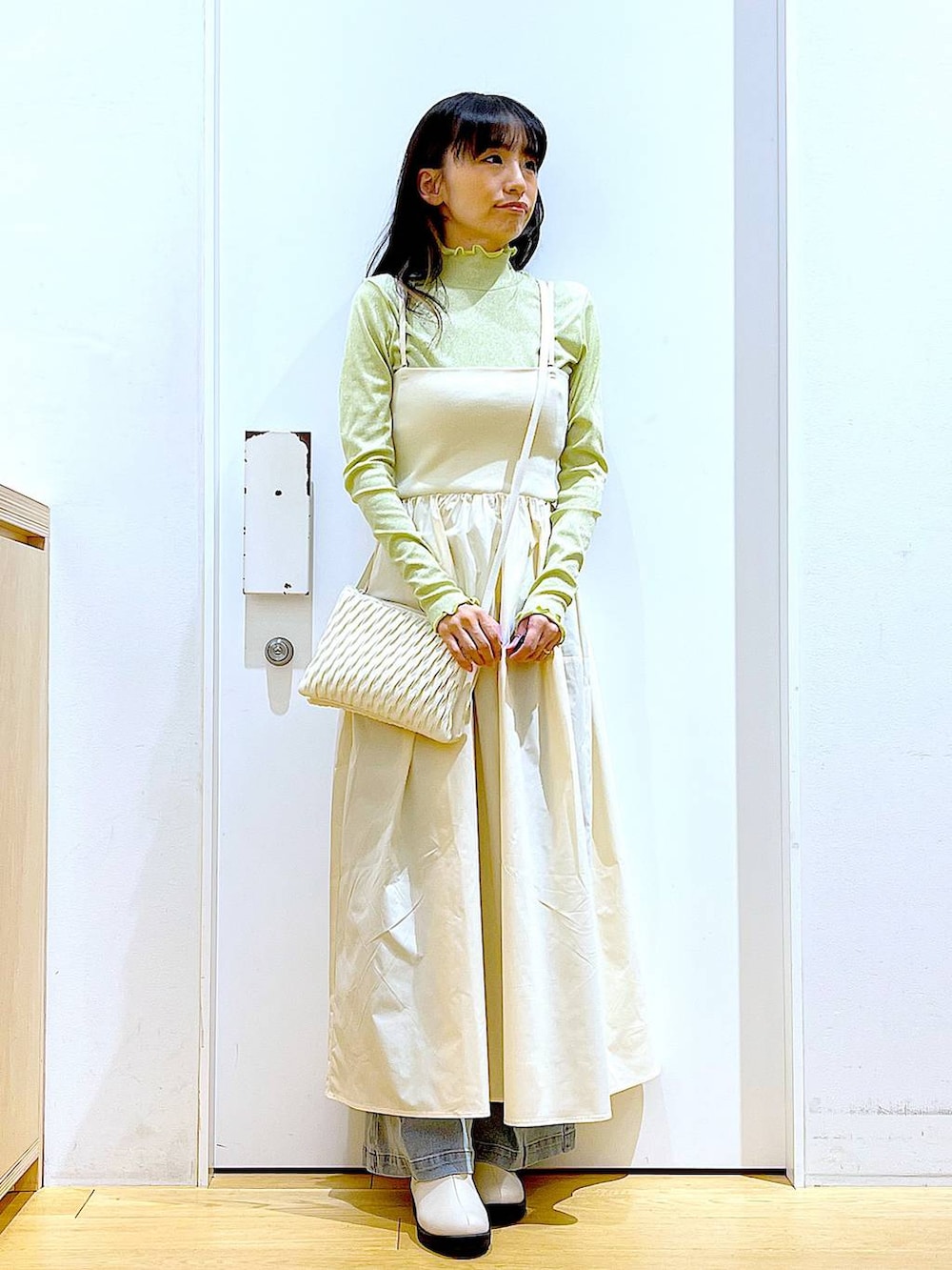 ホワイト系のショルダーバッグ、ベージュ系のブーツ、ブルー系のデニムパンツを着用したレディースの冬コーディネートの2枚目の写真