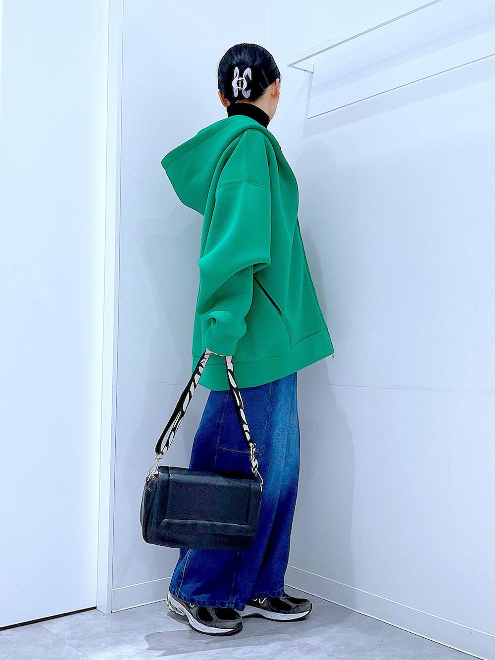 ブラック系のショルダーバッグ、ブラック系のニット/セーター、ブルー系のデニムパンツを着用したレディースの冬コーディネートの4枚目の写真