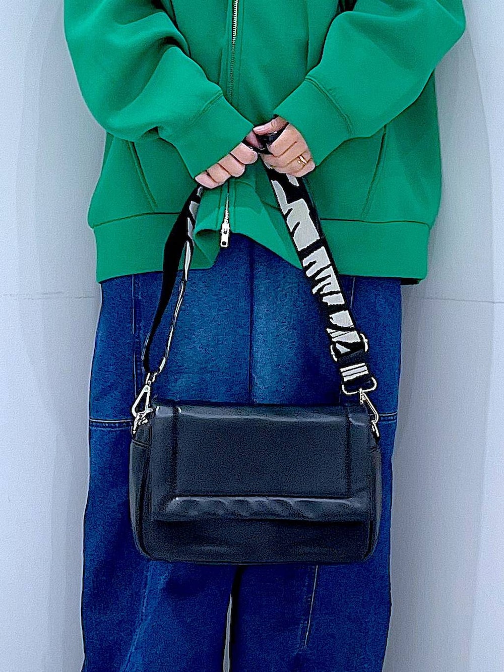 ブラック系のショルダーバッグ、ブラック系のニット/セーター、ブルー系のデニムパンツを着用したレディースの冬コーディネートの9枚目の写真