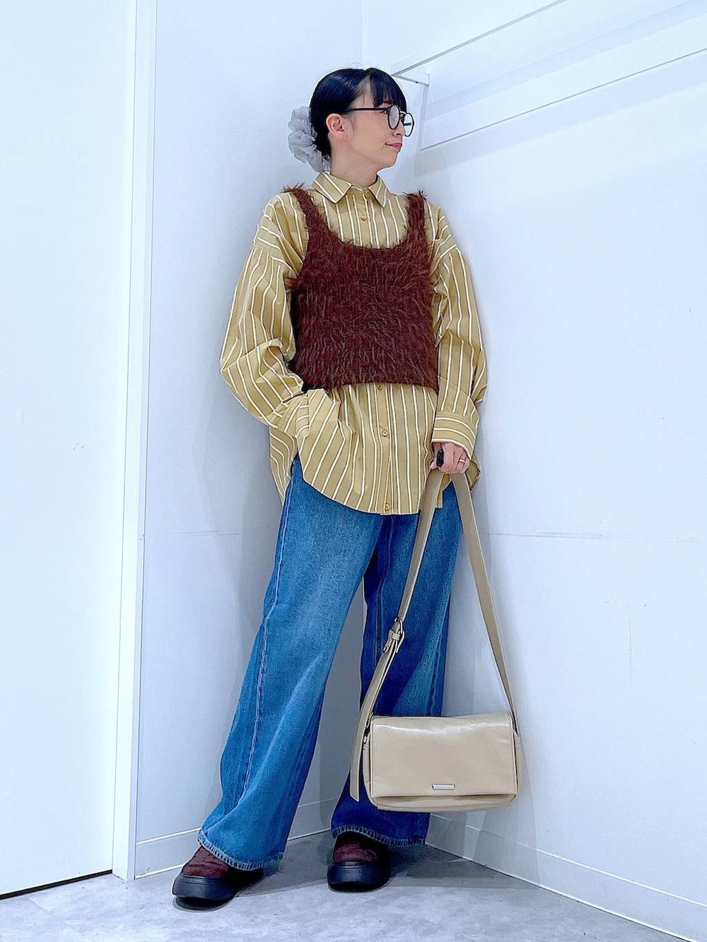 ブルー系のデニムパンツ、イエロー系のシャツ/ブラウス、ブラウン系のベストを着用したレディースの秋コーディネートの2枚目の写真