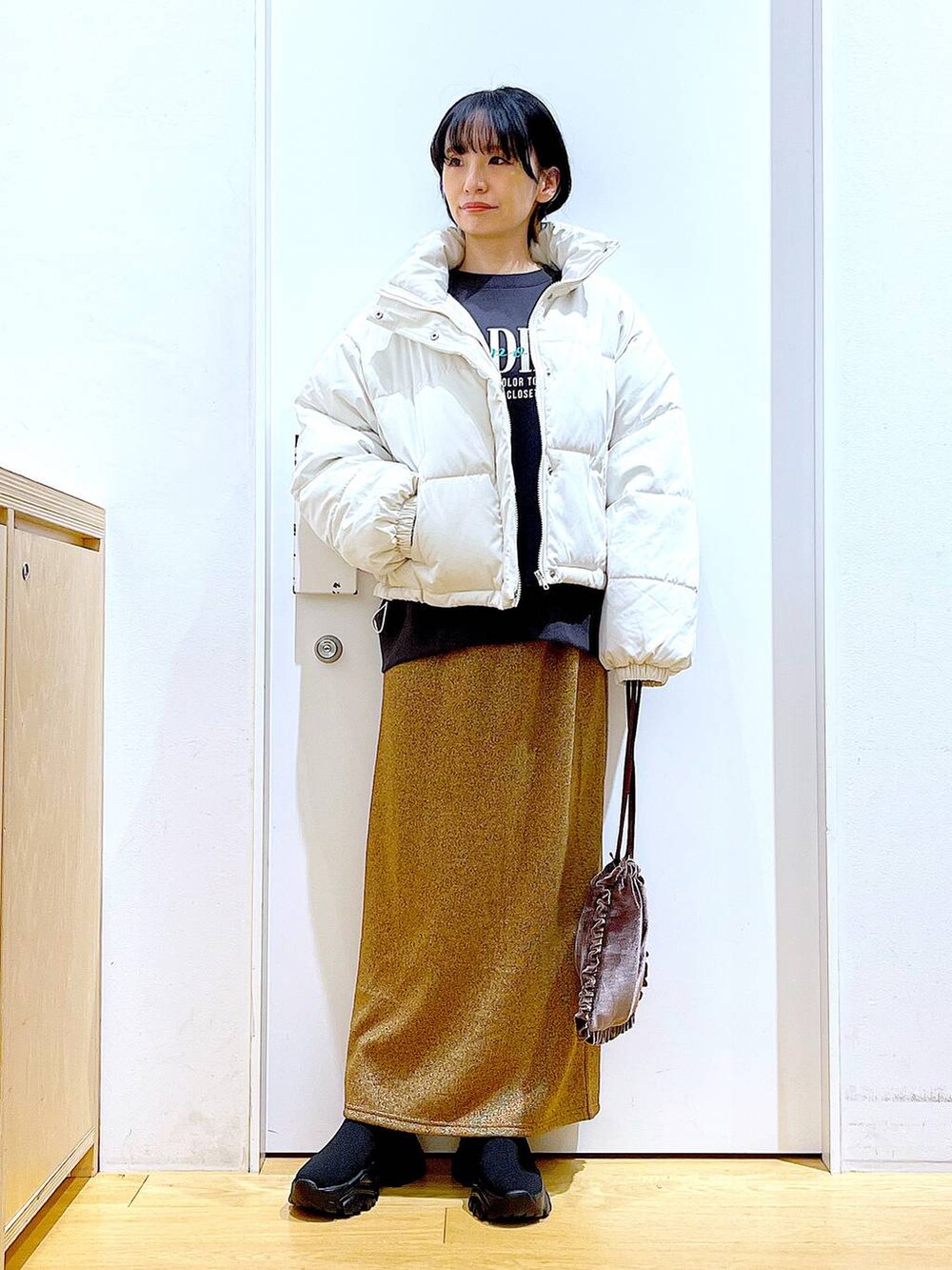 ベージュ系のブルゾン、ブラウン系のショルダーバッグ、ブラック系のブーツを着用したレディースの冬コーディネートの2枚目の写真