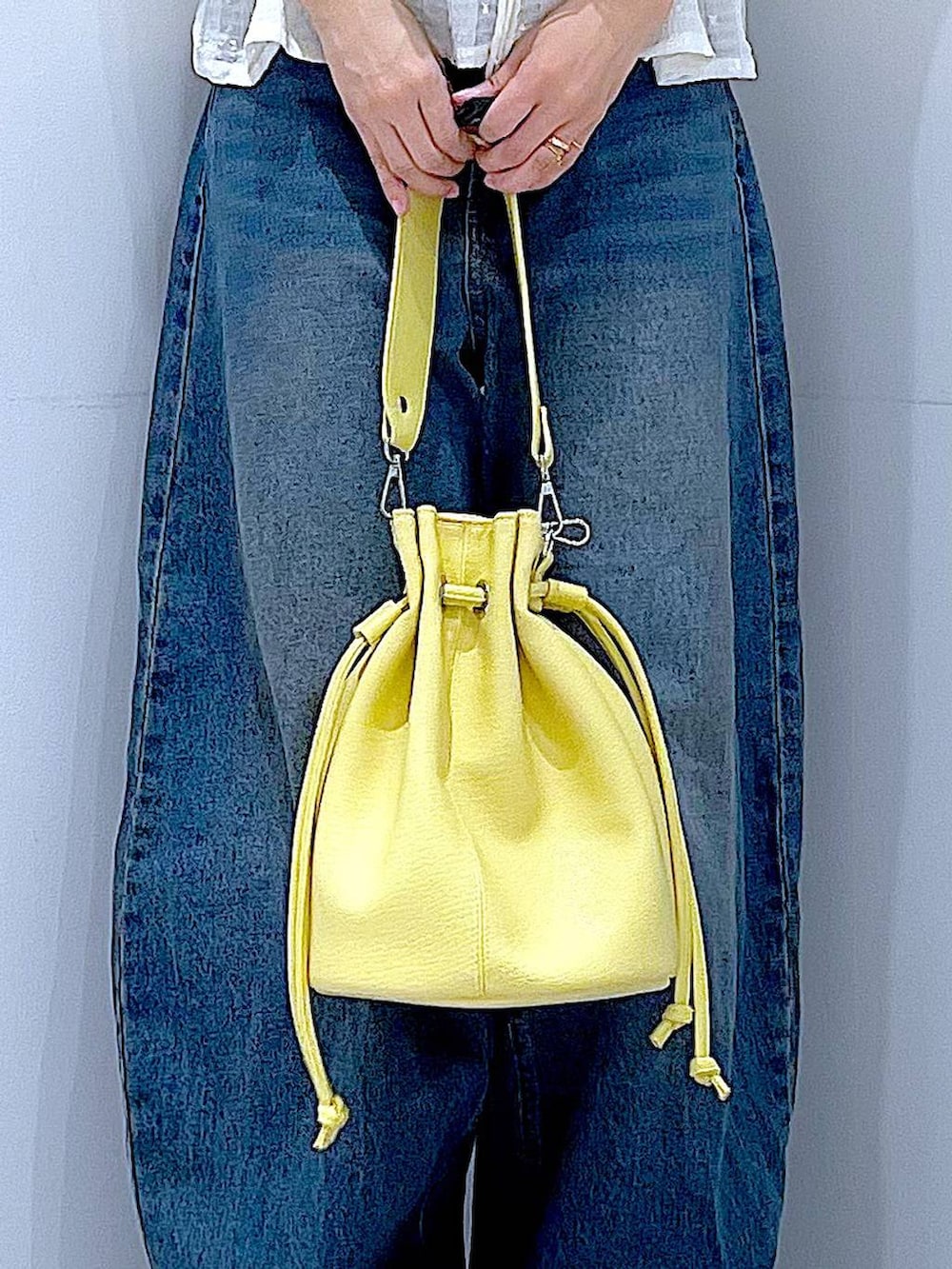 ブルー系のデニムパンツ、イエロー系のショルダーバッグ、ブラック系のスニーカーを着用したレディースの春コーディネートの9枚目の写真