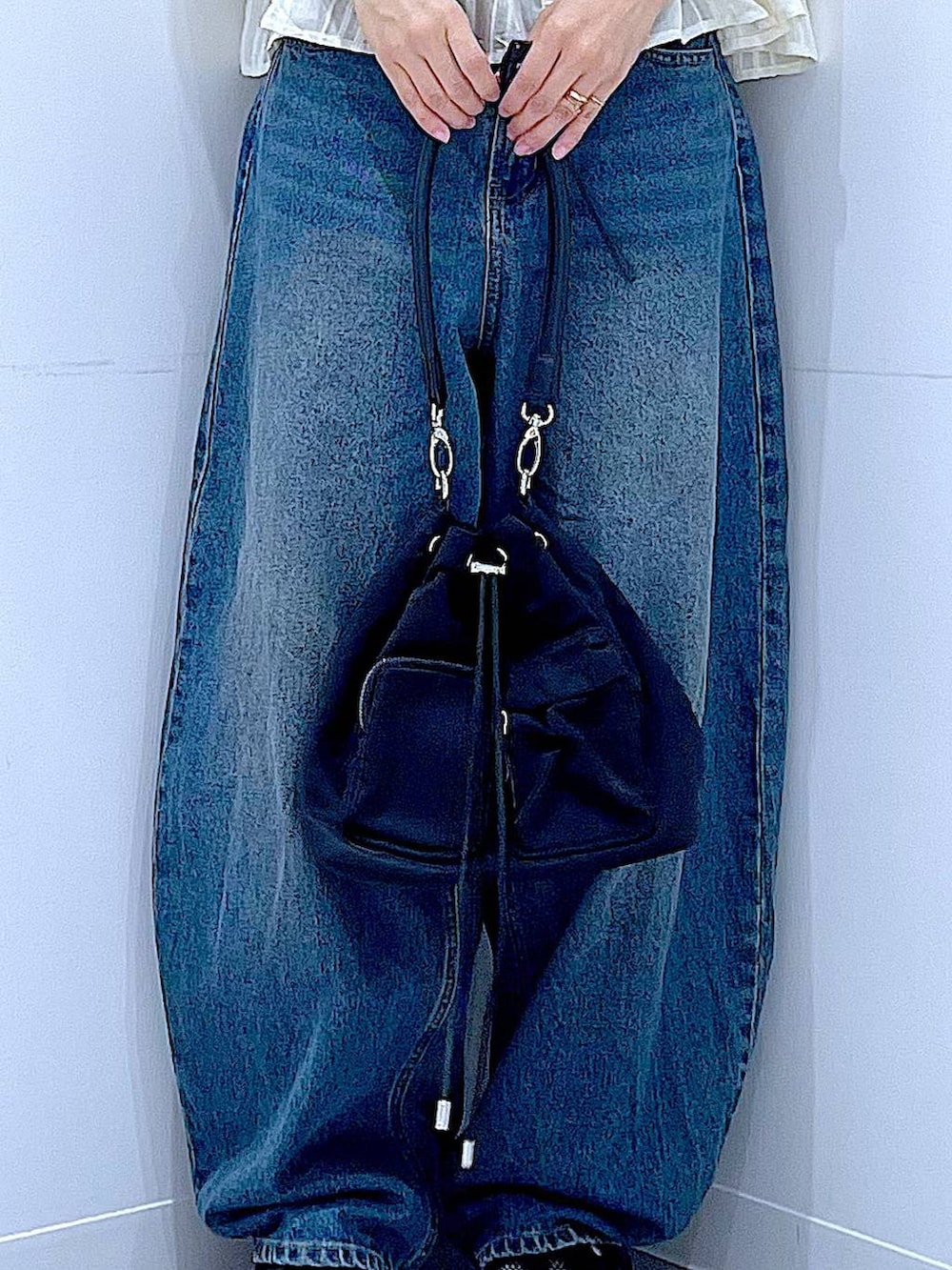 ブルー系のデニムパンツ、ブラック系のスニーカー、ブラック系のショルダーバッグを着用したレディースの春コーディネートの9枚目の写真