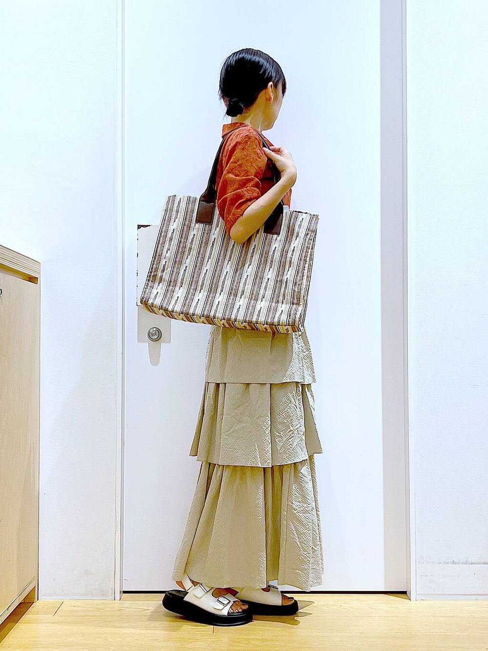 ホワイト系のサンダル、ベージュ系のスカート、レッド系のシャツ/ブラウスを着用したレディースの夏コーディネートの4枚目の写真