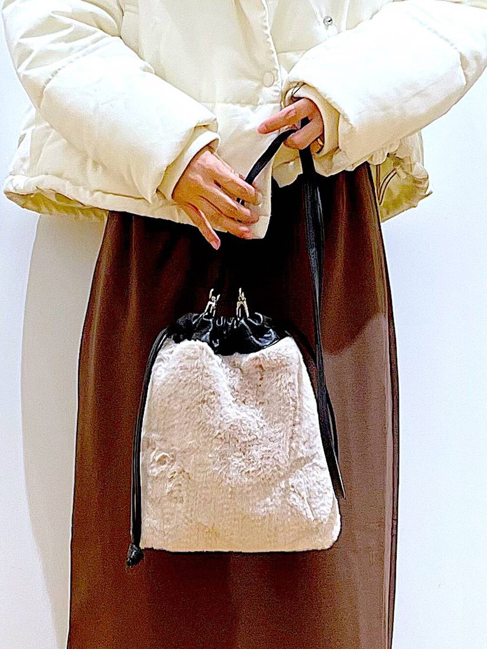 ベージュ系のショルダーバッグ、ブラック系のブーツ、ベージュ系のナイロンジャケットを着用したレディースの冬コーディネートの9枚目の写真