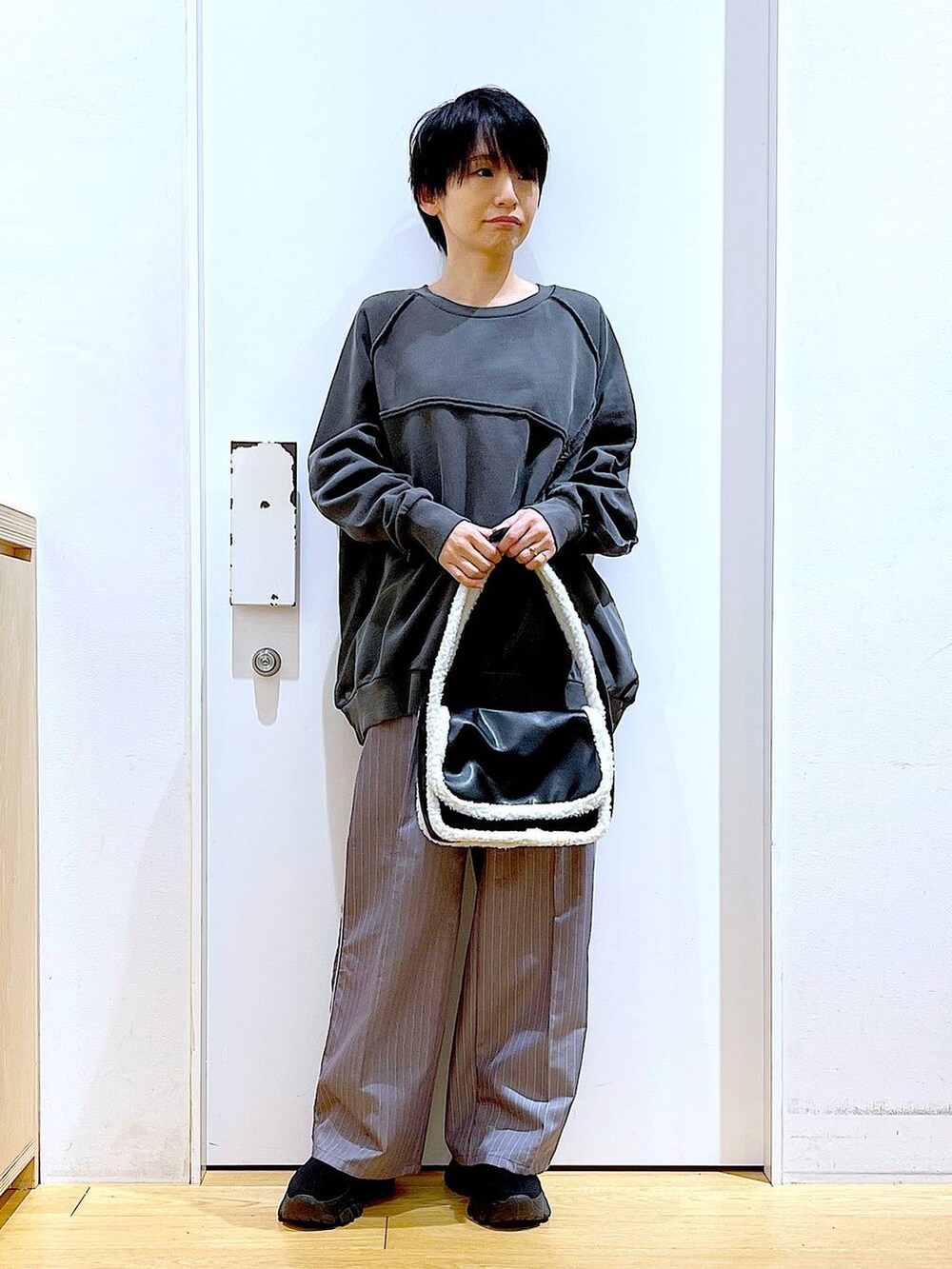 グレー系のスラックス、ブラック系のショルダーバッグ、ブラック系のブーツを着用したレディースの冬コーディネートの2枚目の写真