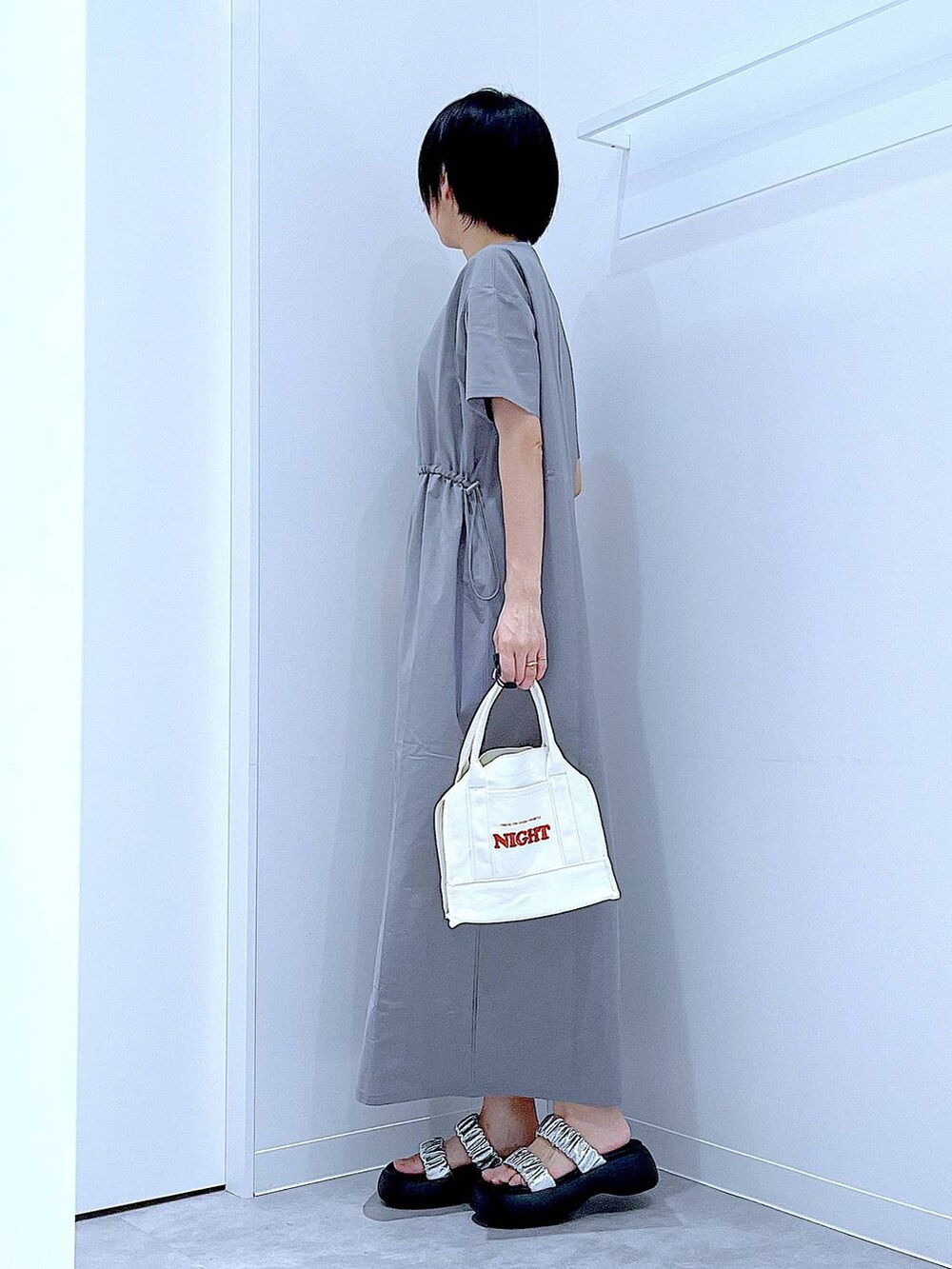 シルバー系のサンダル、グレー系のワンピース、ホワイト系のトートバッグを着用したレディースの夏コーディネートの3枚目の写真
