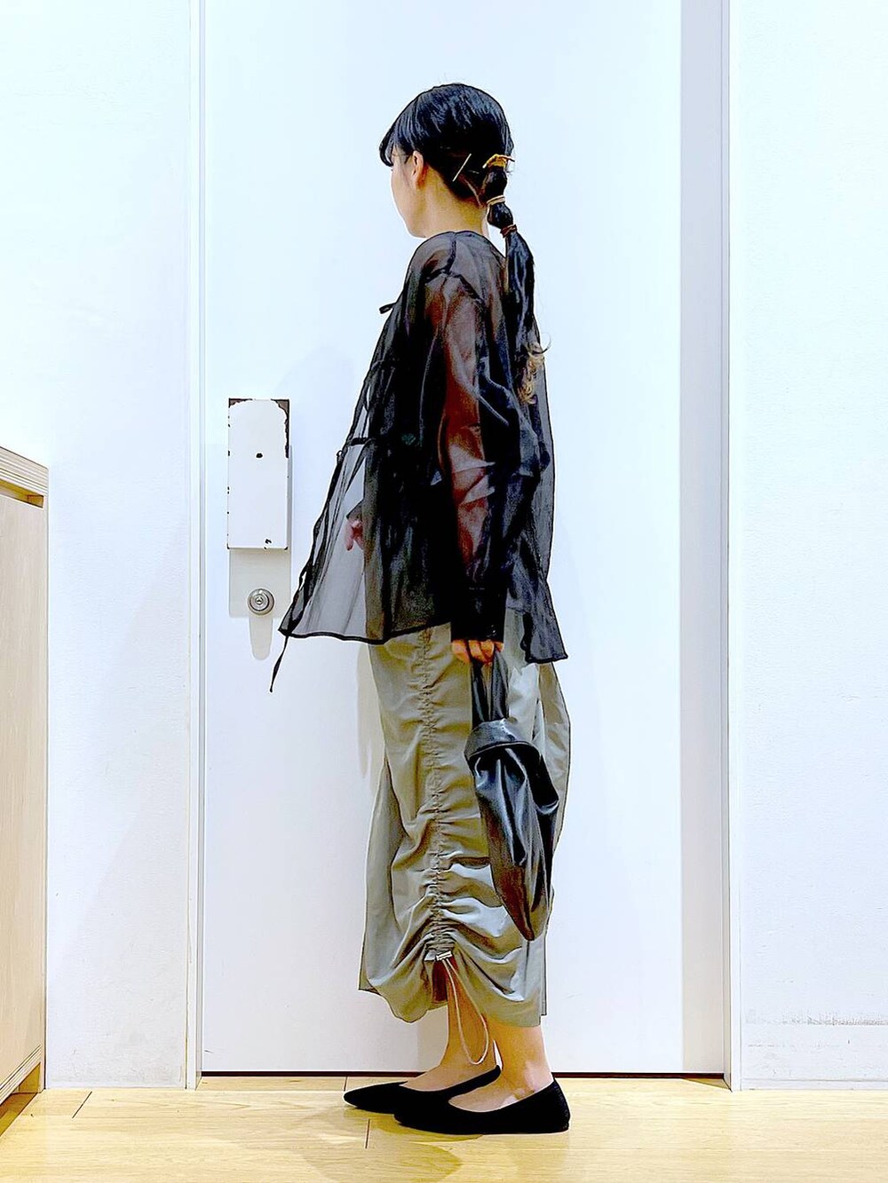 ブラック系のショルダーバッグ、ブラック系のパンプス、グリーン系のワンピースを着用したレディースの春コーディネートの3枚目の写真