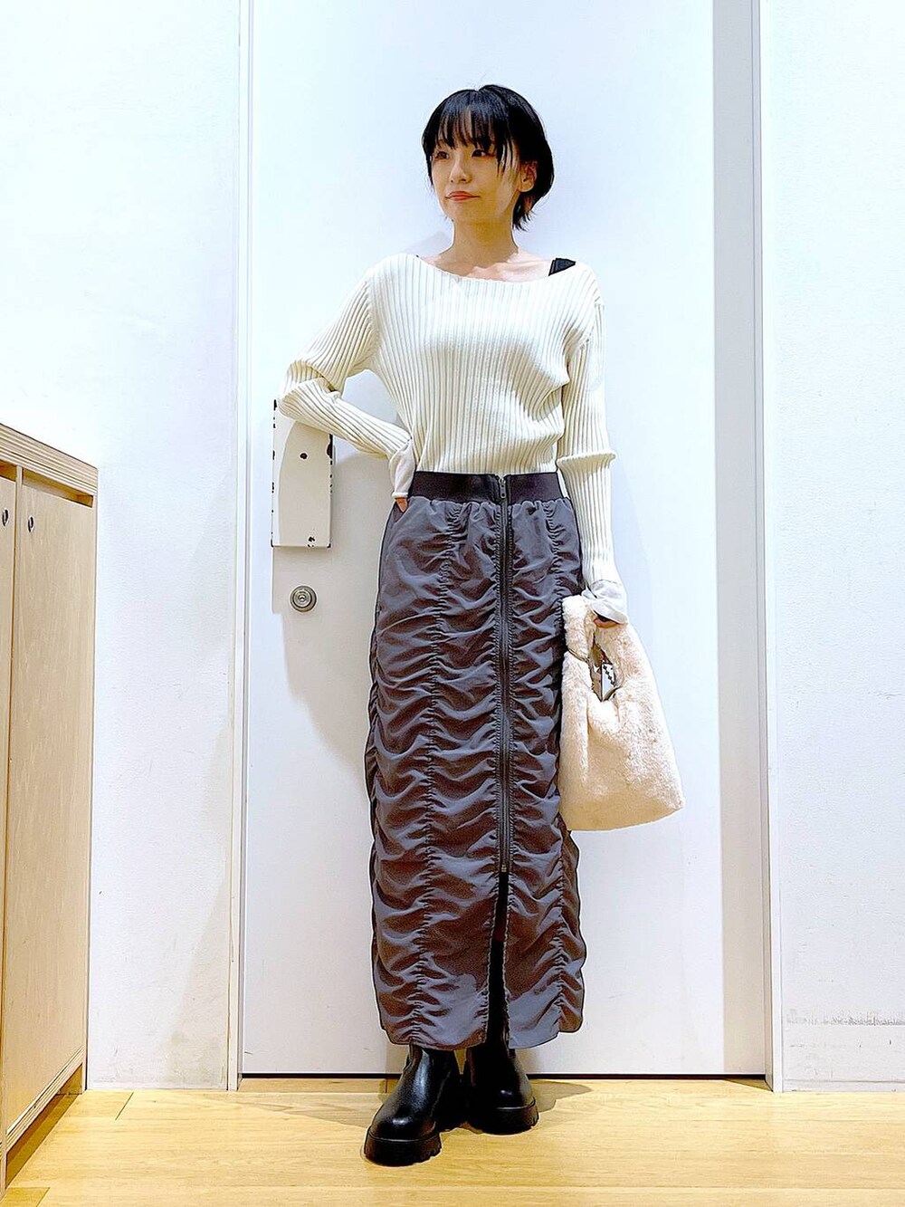 ホワイト系のニット/セーター、ホワイト系のショルダーバッグ、ブラック系のブーツを着用したレディースの秋コーディネートの2枚目の写真