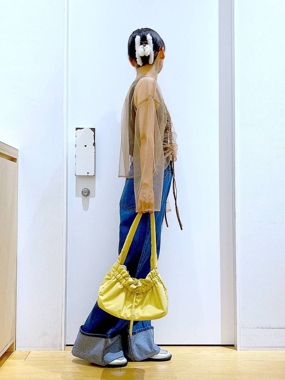 イエロー系のハンドバッグ、シルバー系のローファー、ブルー系のデニムパンツを着用したレディースの秋コーディネートの4枚目の写真