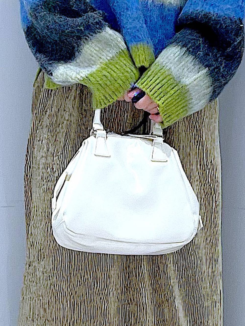 ブラック系のブーツ、ホワイト系のショルダーバッグ、ブルー系のニット/セーターを着用したレディースの冬コーディネートの9枚目の写真