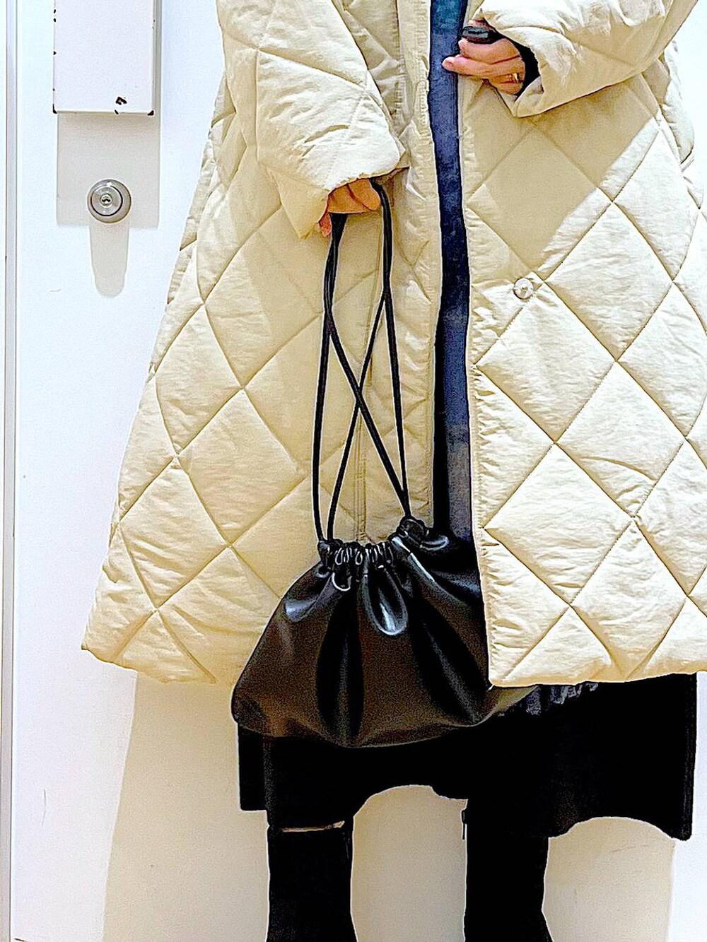 ブラック系のショルダーバッグ、ブラック系のブーツ、ベージュ系のノーカラーコートを着用したレディースの冬コーディネートの9枚目の写真