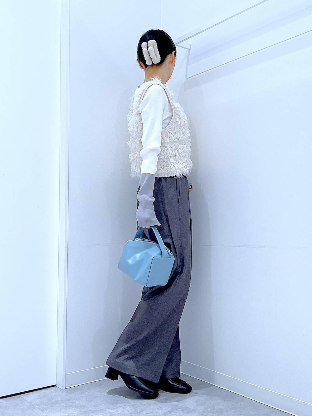 ブラック系のブーツ、グレー系のスラックス、ホワイト系のベストを着用したレディースの冬コーディネートの4枚目の写真