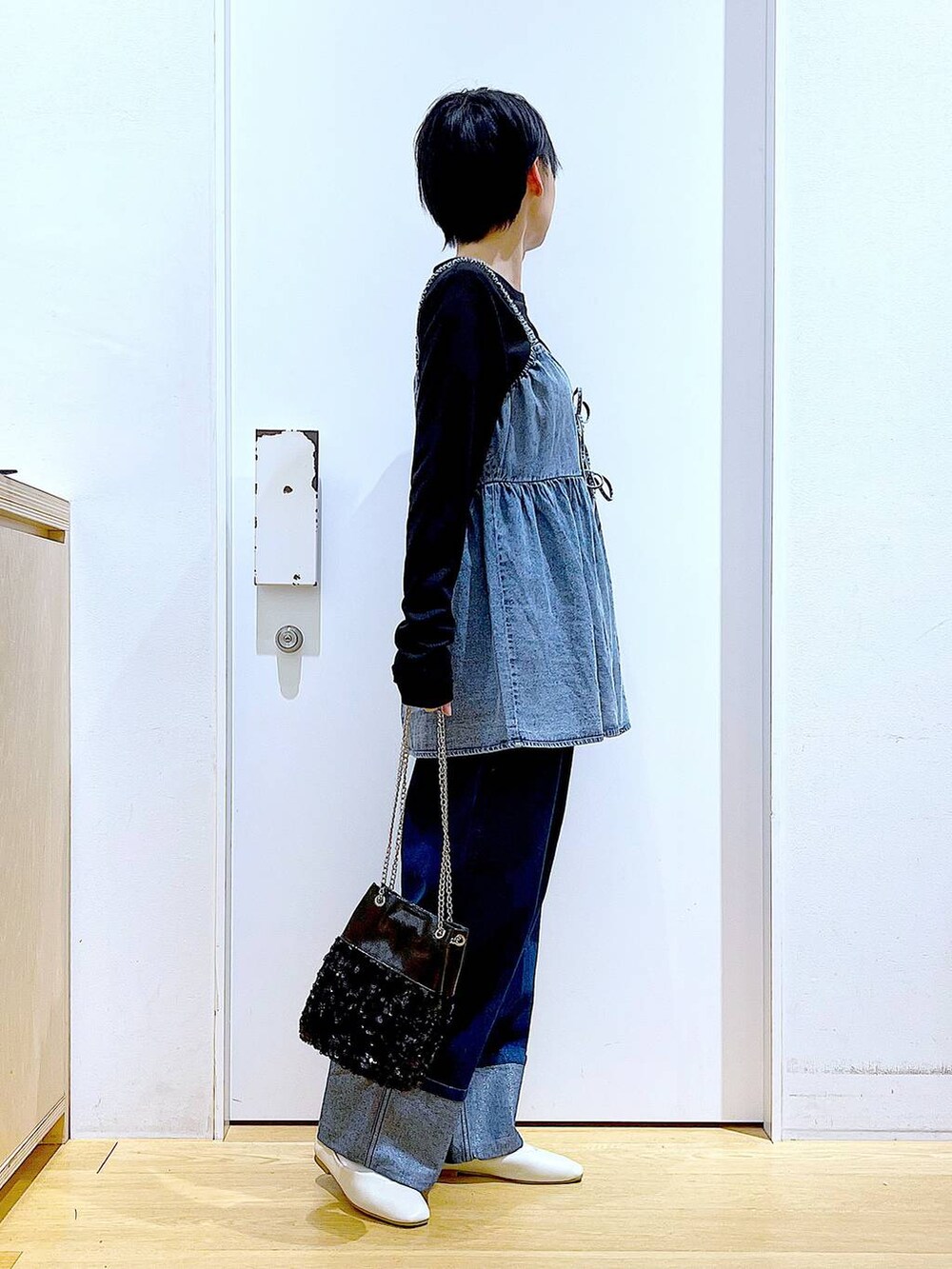 ホワイト系のパンプス、ブルー系のデニムパンツ、ブラック系のショルダーバッグを着用したレディースの春コーディネートの4枚目の写真