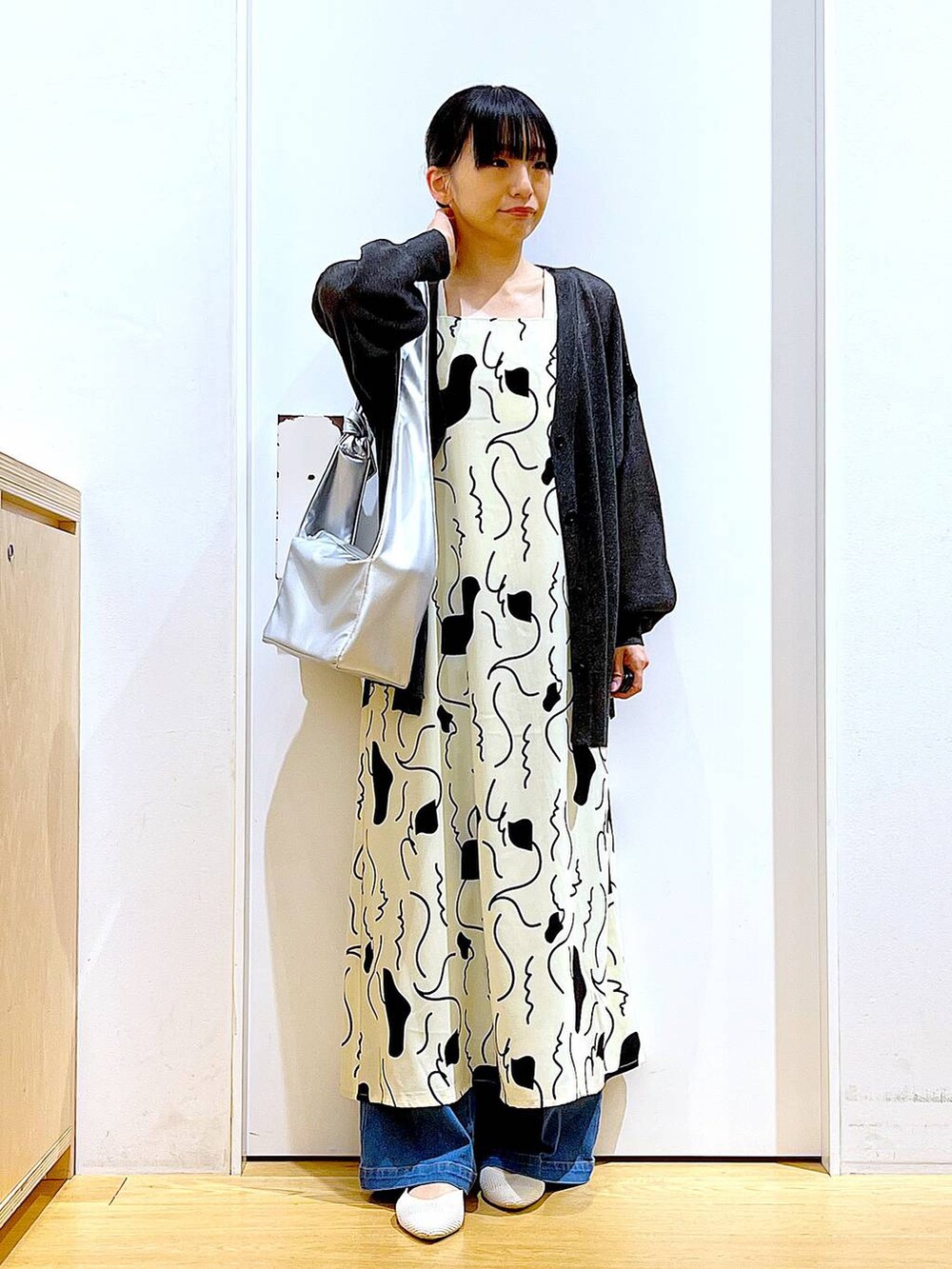 ブルー系のデニムパンツ、ベージュ系のワンピース、シルバー系のショルダーバッグを着用したレディースの春コーディネートの2枚目の写真