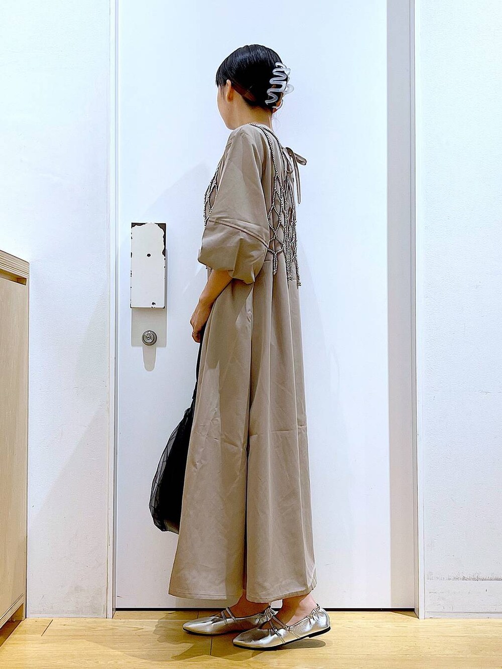 ブラック系のトートバッグ、ベージュ系のワンピース、シルバー系のパンプスを着用したレディースの夏コーディネートの3枚目の写真