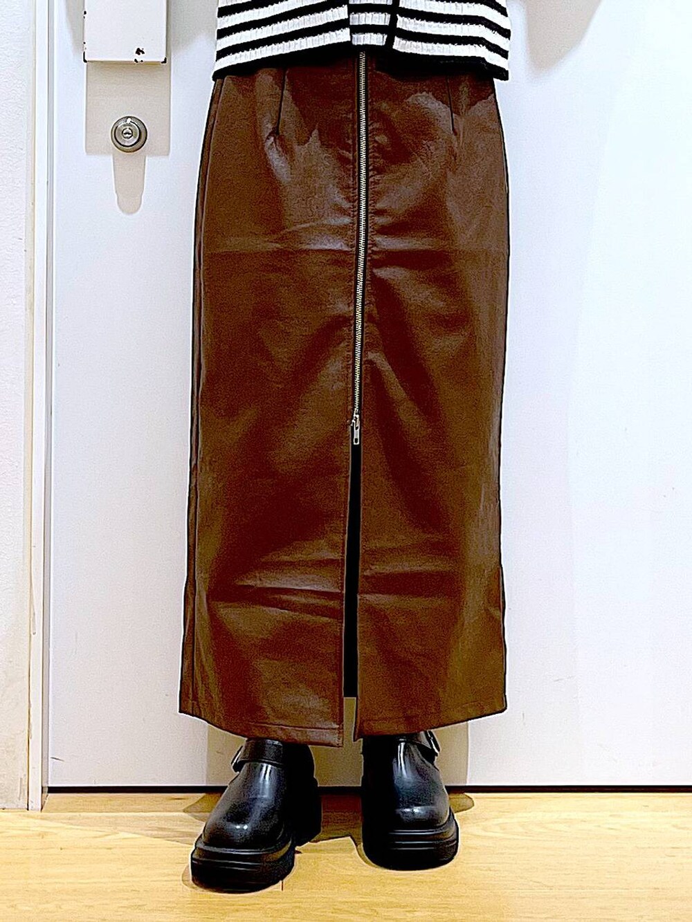 ブラウン系のスカート、ホワイト系のショルダーバッグ、ブラック系のブーツを着用したレディースの秋コーディネートの8枚目の写真