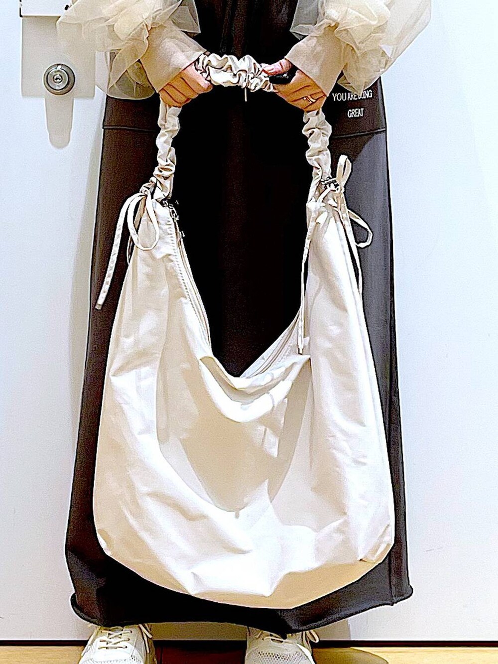 ホワイト系のショルダーバッグ、ホワイト系のスニーカー、グレー系のスカートを着用したレディースの春コーディネートの9枚目の写真