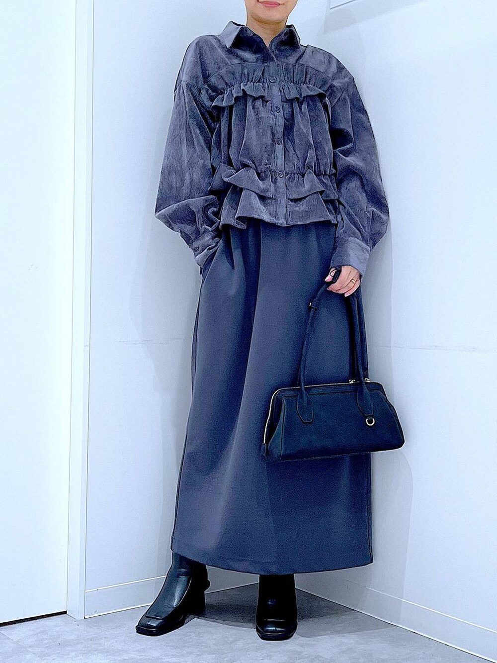 グレー系のスカート、ブラック系のブーツ、ブラック系のハンドバッグを着用したレディースの秋コーディネートの6枚目の写真