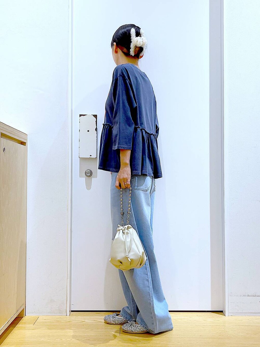 ブラック系のショルダーバッグ、ブルー系のデニムパンツ、シルバー系のパンプスを着用したレディースの秋コーディネートの3枚目の写真