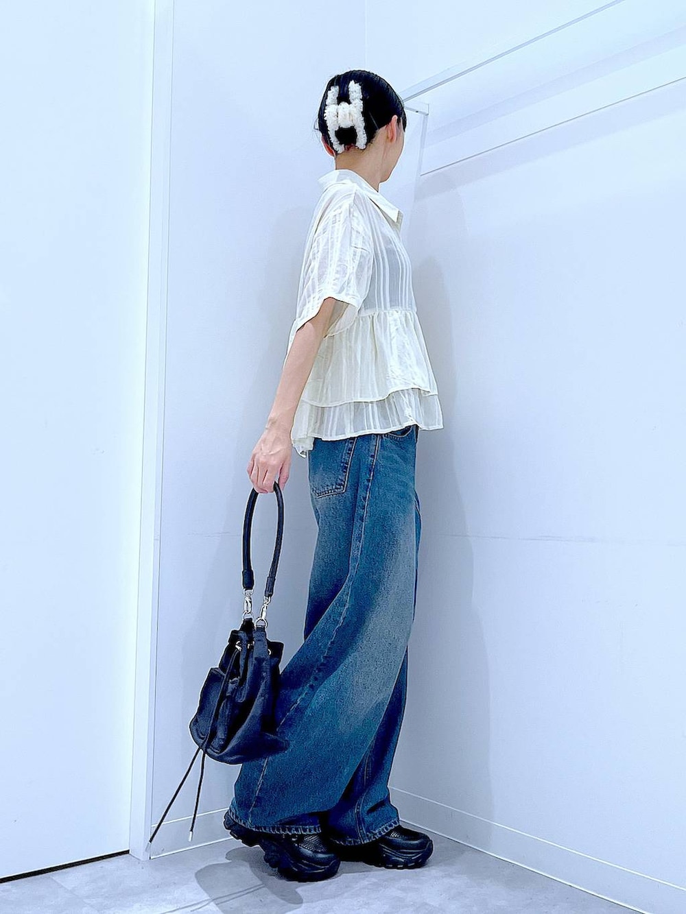 ブルー系のデニムパンツ、ブラック系のスニーカー、ブラック系のショルダーバッグを着用したレディースの春コーディネートの4枚目の写真