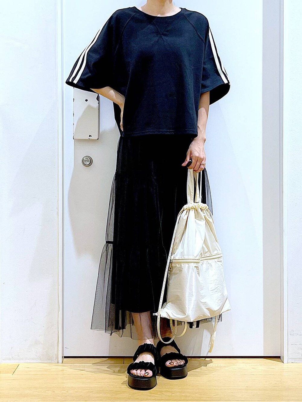 ホワイト系のバックパック/リュック、ブラック系のサンダル、ブラック系のスカートを着用したレディースの夏コーディネートの6枚目の写真