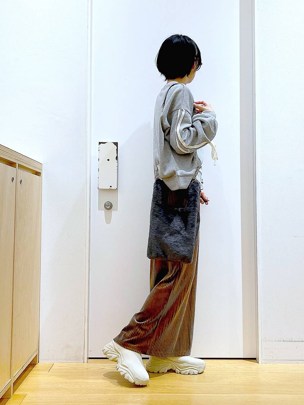 グレー系のショルダーバッグ、ブラウン系のスカート、ベージュ系のブーツを着用したレディースの秋コーディネートの4枚目の写真