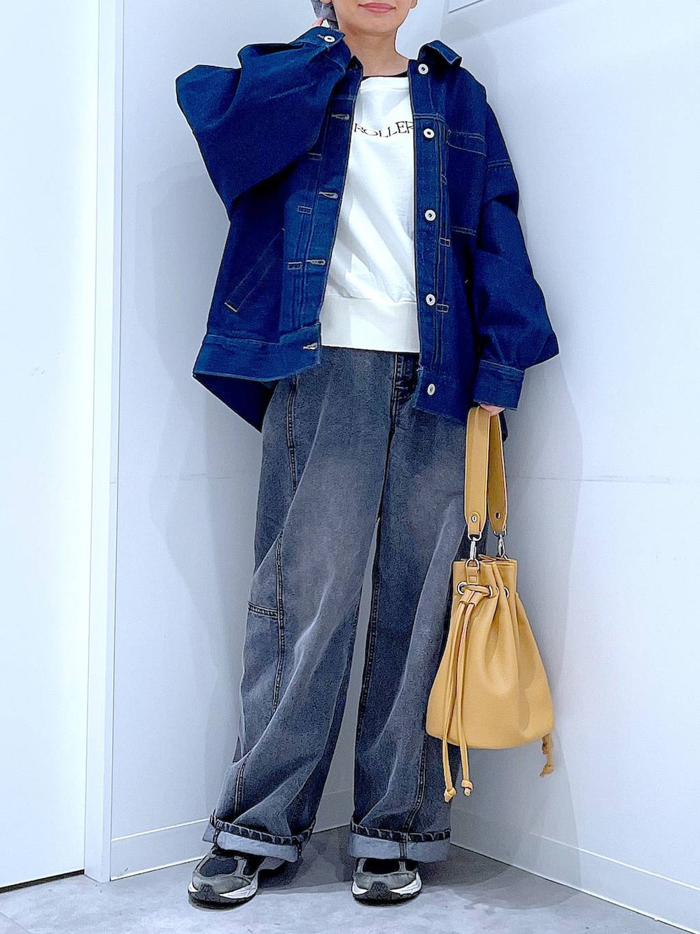 ブルー系のデニムジャケット、ブラック系のデニムパンツ、ブラウン系のショルダーバッグを着用したレディースの春コーディネートの6枚目の写真