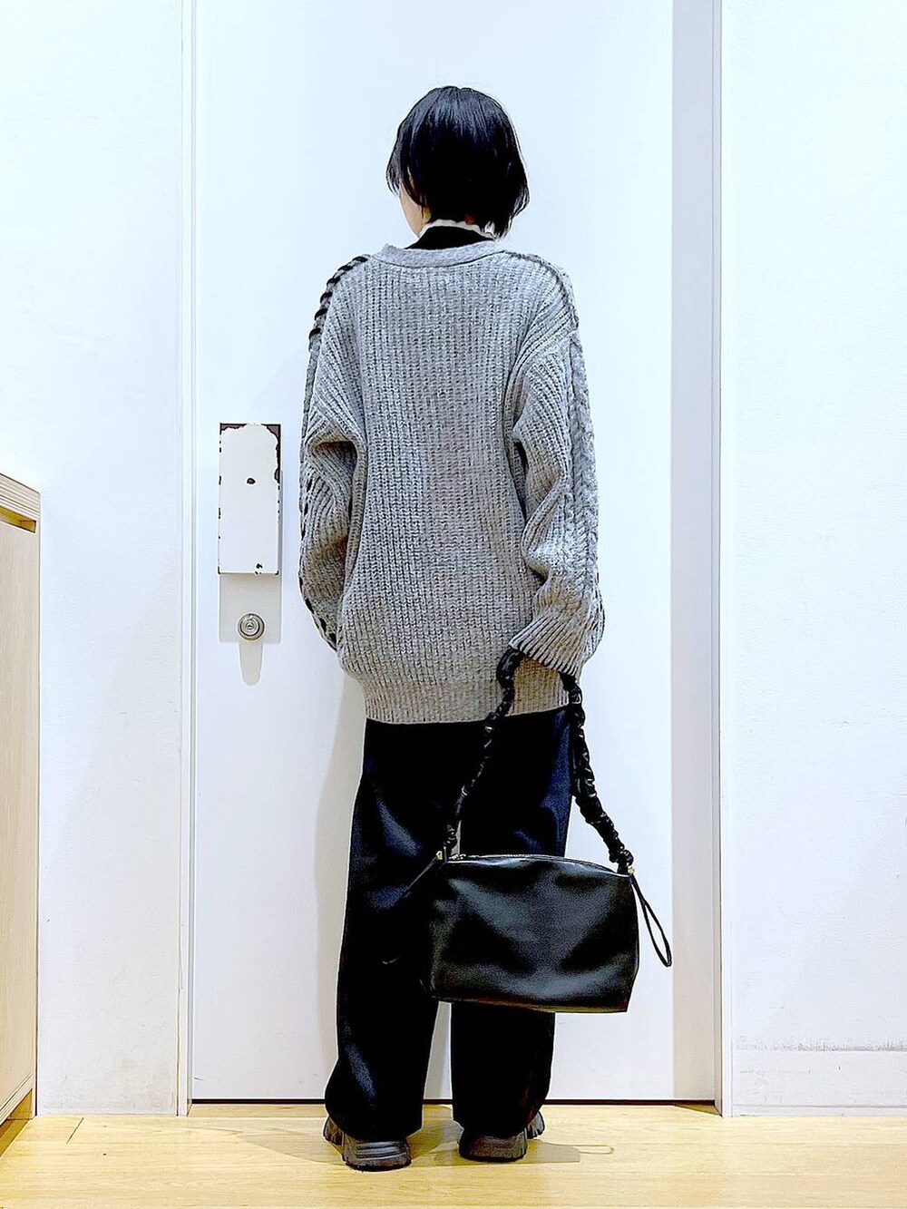 ブラック系のニット/セーター、ブラック系のブーツ、ブラック系のショルダーバッグを着用したレディースの冬コーディネートの5枚目の写真