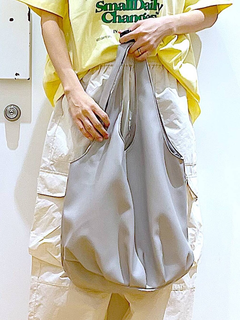 グレー系のトートバッグ、ホワイト系のカーゴパンツ、ホワイト系のパンプスを着用したレディースの春コーディネートの9枚目の写真