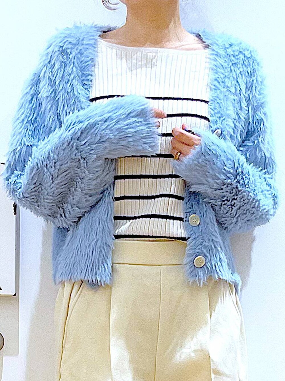 シルバー系のショルダーバッグ、ベージュ系のブーツ、ホワイト系のニット/セーターを着用したレディースの冬コーディネートの7枚目の写真