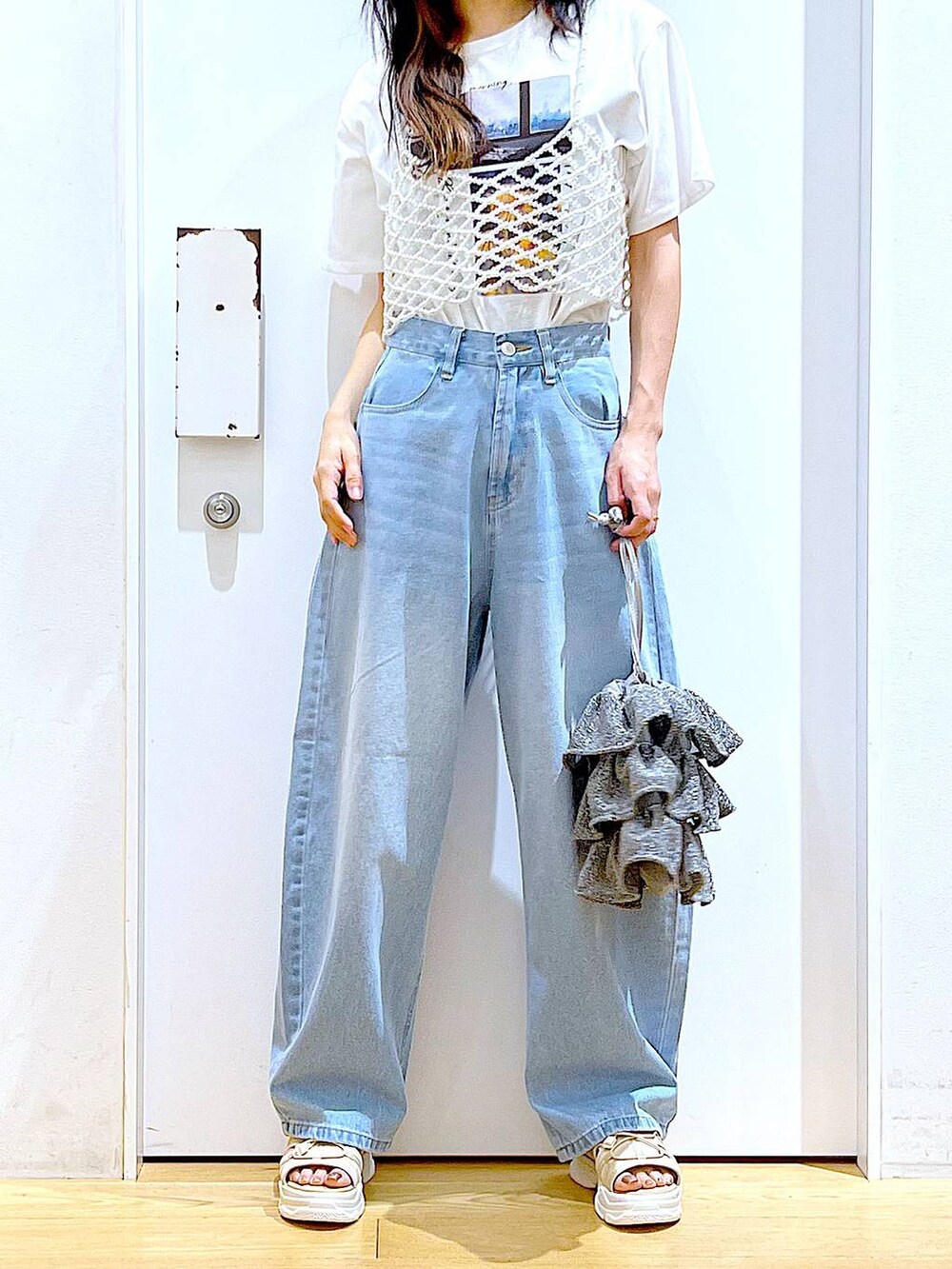 シルバー系のショルダーバッグ、ベージュ系のサンダル、ブルー系のデニムパンツを着用したレディースの夏コーディネートの6枚目の写真