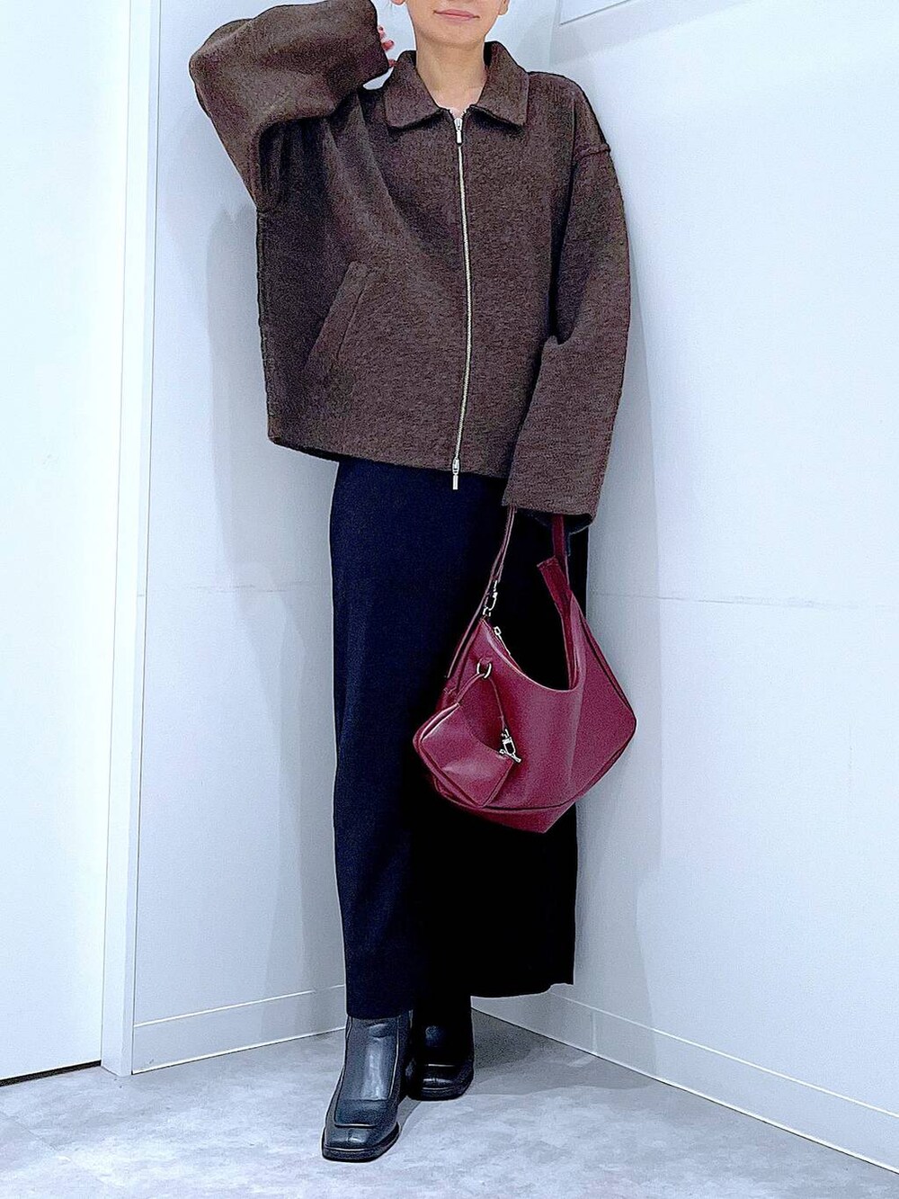 ブラウン系のブルゾン、ブラック系のブーツ、レッド系のショルダーバッグを着用したレディースの秋コーディネートの6枚目の写真