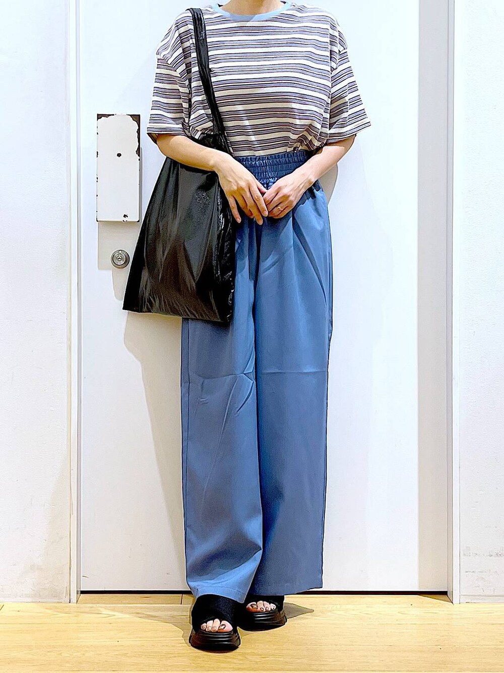 ブラック系のトートバッグ、ブラック系のサンダル、ベージュ系のTシャツ/カットソーを着用したレディースの夏コーディネートの6枚目の写真