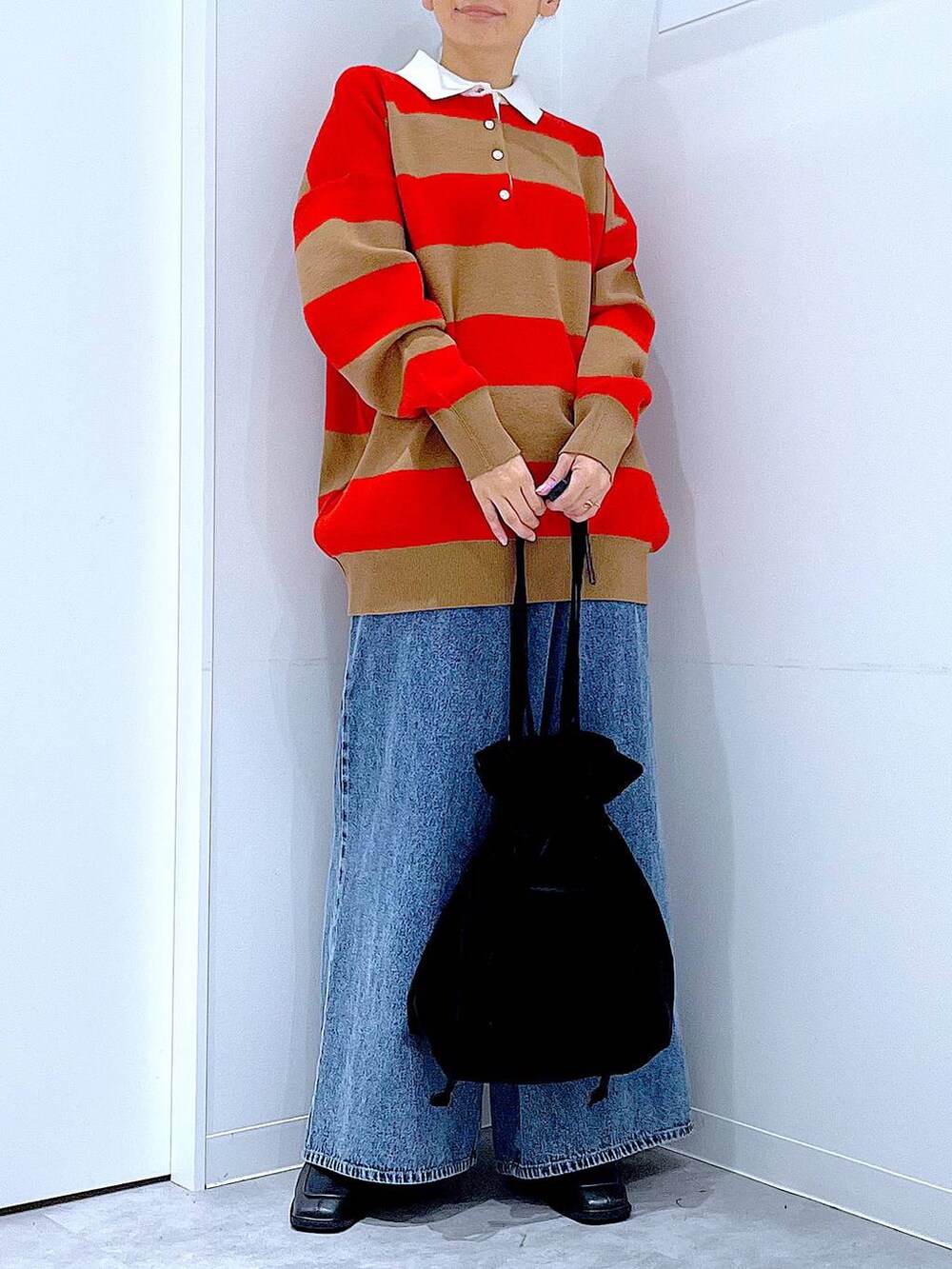 ブラック系のトートバッグ、レッド系のニット/セーター、ブルー系のデニムパンツを着用したレディースの冬コーディネートの6枚目の写真