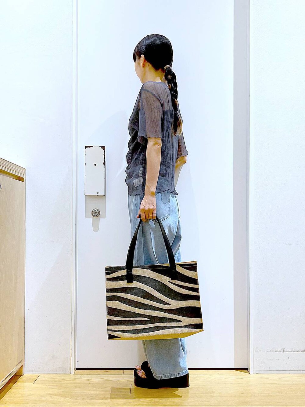 ブルー系のデニムパンツ、その他のトートバッグ、ブラック系のサンダルを着用したレディースの夏コーディネートの3枚目の写真