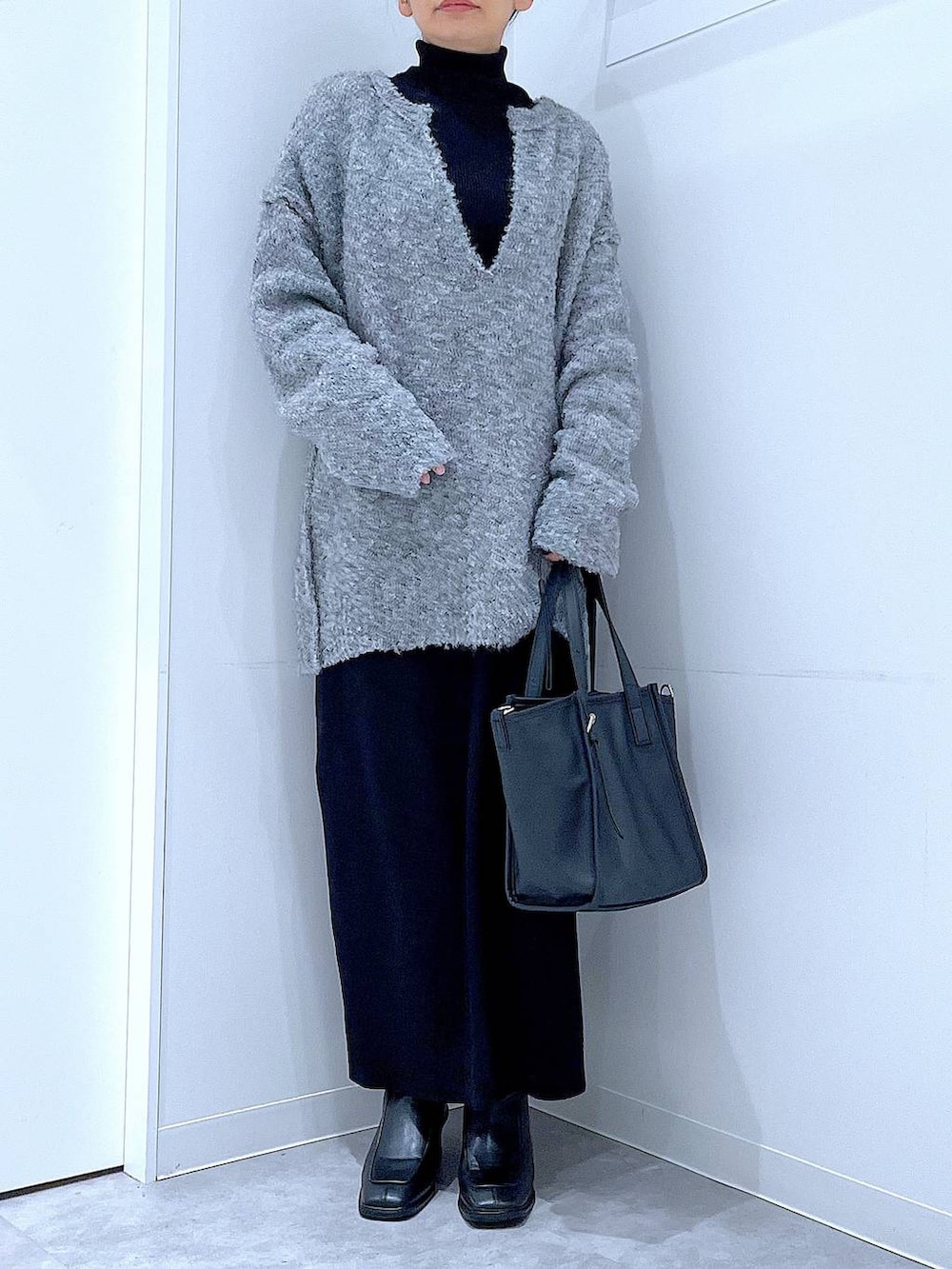 ブラック系のブーツ、グレー系のニット/セーター、ブラック系のスカートを着用したレディースの冬コーディネートの6枚目の写真